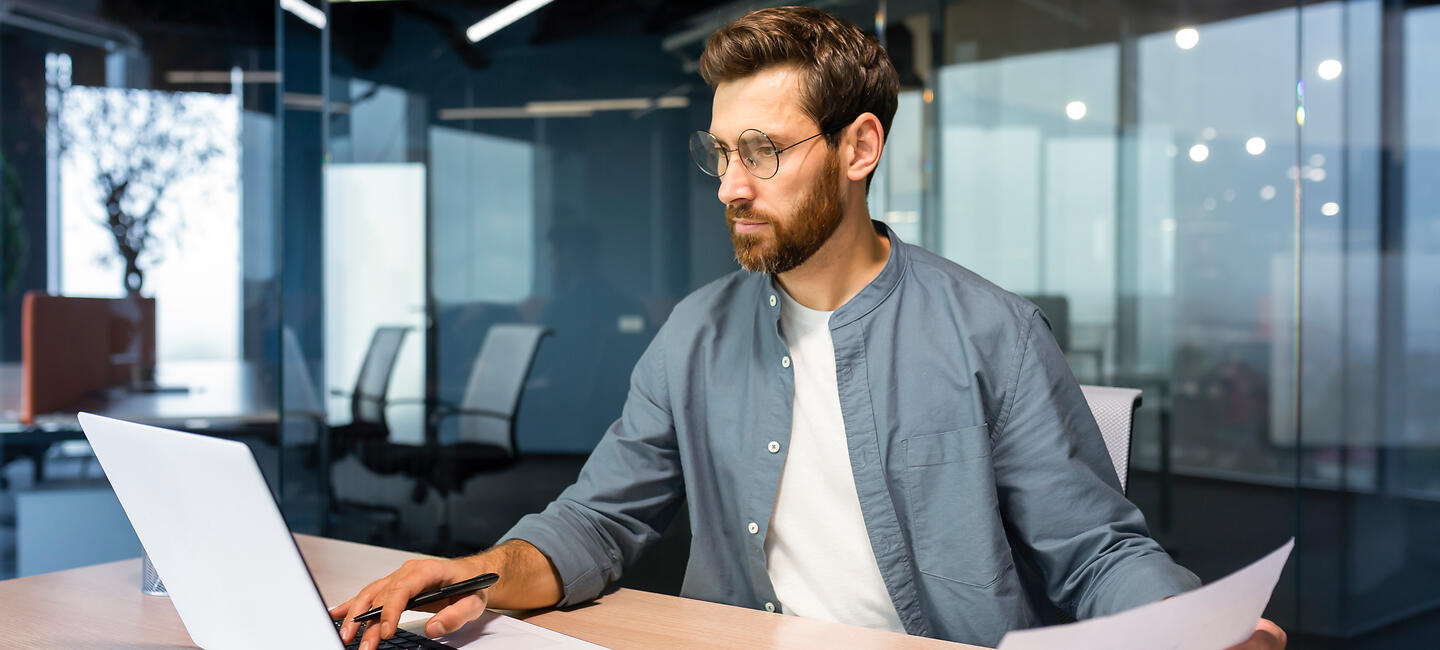 Mann vergleicht verschiedene Angebote zur Berufsunfähigkeitsversicherung am Laptop
